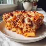 A generous serving of baked Irresistible Mostaccioli pasta layered with rich meat sauce and melted, browned cheese.