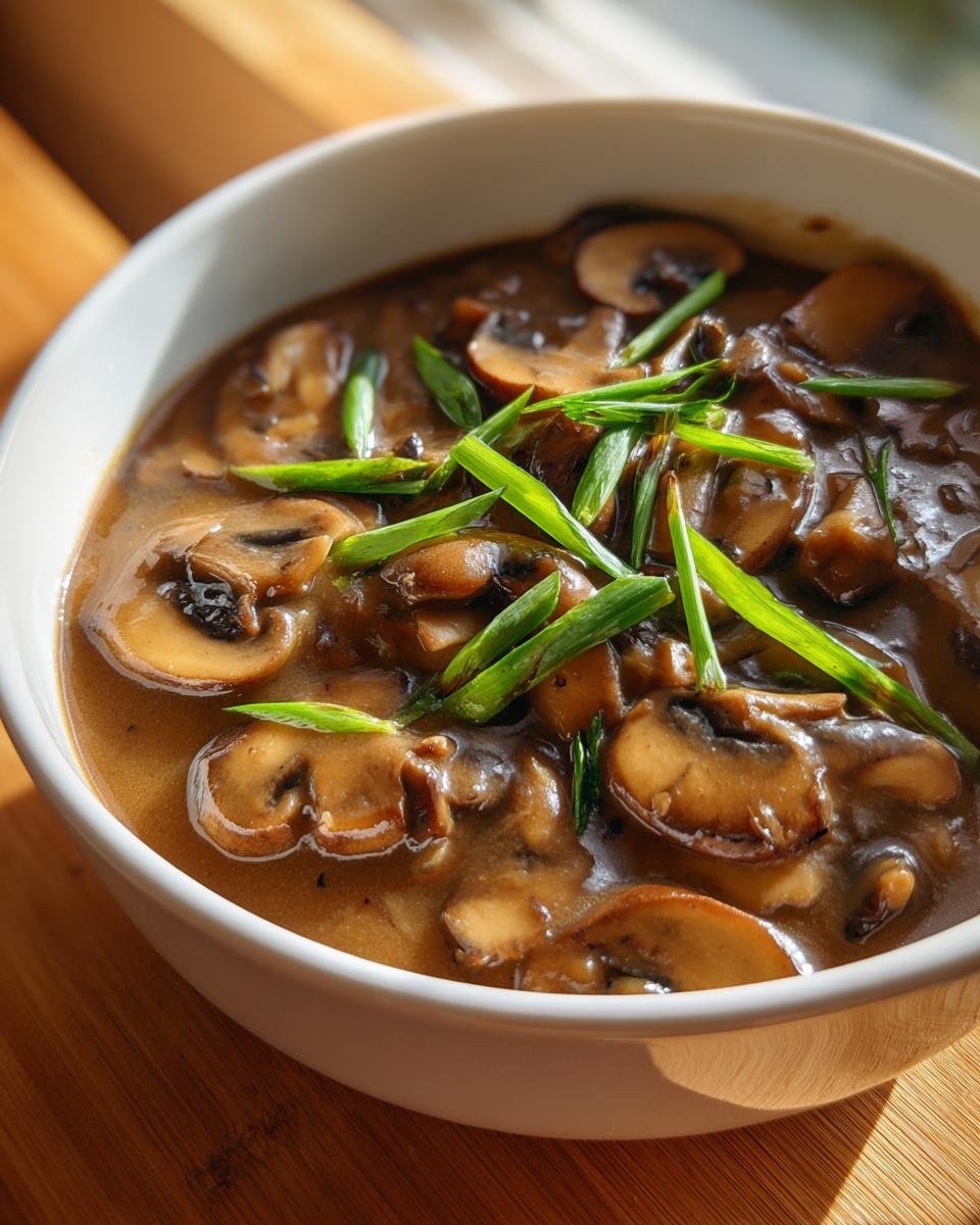 Close-up of rich, brown Irresistible Mushroom Leek Gravy With Shallots, topped with fresh green scallions.