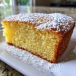 Close-up of a moist slice of Irresistible Olive Oil Cake dusted generously with powdered sugar.