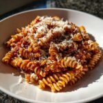A close-up of Irresistible Rotini Pasta Recipe tossed in a rich red sauce and topped generously with grated Parmesan cheese.
