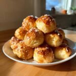 A stack of golden brown Irresistible Soft Pretzel Bites sprinkled with coarse salt on a white plate.