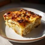 A close-up of a cheesy, layered slice from the Irresistible Thanksgiving Veggie Gratin Recipe on a light plate.