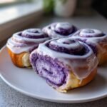 Four Irresistible Vegan Ube Rolls, drizzled with white icing, served on a white plate.