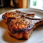 Close-up of two perfectly seared, juicy pork chops coated in a flavorful glaze from the Ultimate Pork Chop Marinade.