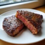 Two thick slices of Marinated Mouth Watering Steak Juicy And Flavor Packed Recipe showing a perfect medium-rare center.