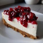 Close-up of a slice of Irresistible Almost No Bake Christmas Cheesecake topped with rich cranberry sauce.