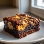 A rich, fudgy slice of peanut butter swirl brownies on a white plate.