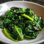 Close-up of vibrant, glossy Quick Swiss Chard Easy Delicious Sauteed Greens seasoned with visible garlic pieces.