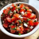 Close-up of fresh, chunky Two Minute Easy Pico De Gallo with diced tomatoes, onions, and cilantro in a white bowl.
