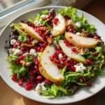 Close-up of a Vibrant Pear Pomegranate Salad Recipe featuring pear slices, feta, walnuts, and bright red pomegranate seeds.