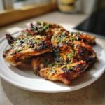 Close-up of grilled Irresistible Vietnamese Lemongrass Chicken pieces garnished with chives on a white plate.