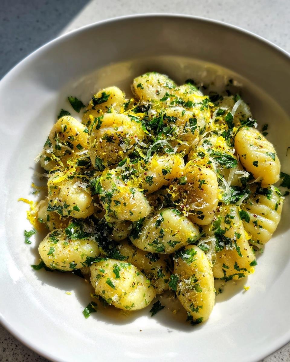 Close-up of cooked gnocchi tossed with lemon zest, Parmesan cheese, and fresh parsley for the Zesty Lemon Parmesan Sheet Pan Gnocchi Recipe Delight.