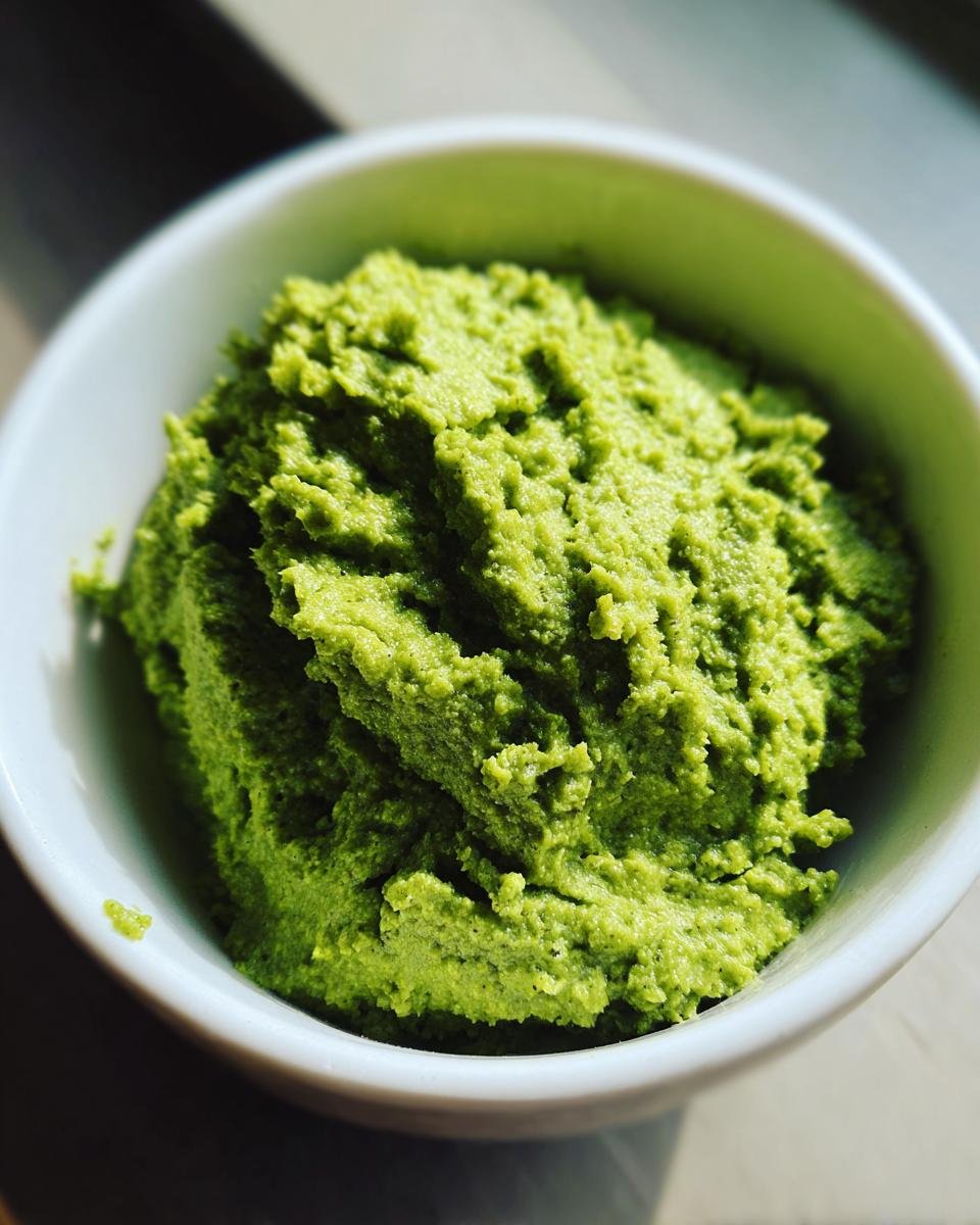 Close-up of a vibrant green, textured 2 Minute Green Olive Dip mounded high in a small white bowl.
