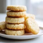 A stack of five golden-brown Almond Flour Sugar Cookies piled high on a white plate.