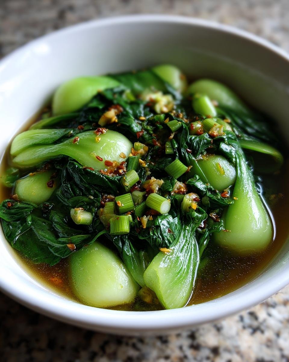 Close-up of vibrant Bok Choy Soup With Garlic And Ginger served in a white bowl, topped with scallions.