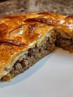 Close-up of a Chinese Crispy Meat Beef Pie cut in half, showing flaky golden pastry and savory ground beef filling.