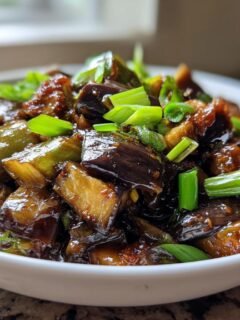 A close-up of glossy, saucy Chinese Eggplant With Garlic Sauce topped with fresh green onions.