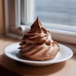 A perfect, tall swirl of rich Chocolate Coconut Whipped Cream piped onto a small white plate.
