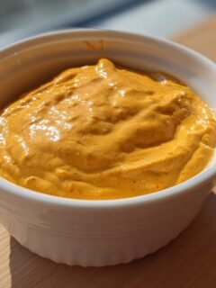 Close-up of thick, creamy orange Southwest Salad Dressing in a small white ramekin.