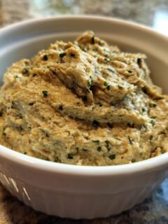A close-up of Easy Tasty Portuguese Canned Sardine Pate, textured and flecked with green herbs, served in a small white ramekin.