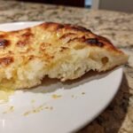 Close-up of a torn piece of fluffy Gluten Free Naan Bread brushed with melted butter.