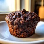 A close-up of a rich, dark Gluten Free Chocolate Zucchini Muffins Paleo topped with melted chocolate chips.