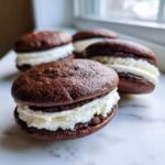 A close-up of a freshly made chocolate Gluten Free Whoopie Pie filled with thick white cream frosting.