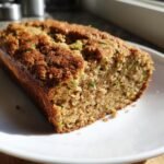 A close-up of a freshly baked loaf of Gluten Free Zucchini Bread showing its moist crumb and green zucchini shreds.