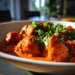 Close-up of tender chicken pieces coated in rich, orange sauce, garnished with fresh cilantro, representing Healthy Chicken Tikka Masala.