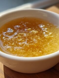 Close-up of a small white bowl filled with glistening, golden This Lemongrass Sauce Will Change Your Cooking Forever, showing minced ingredients.