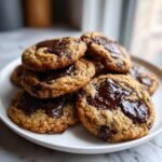 A stack of freshly baked Paleo Chewy Chocolate Chip Cookies with melted, glossy chocolate pools on top.