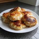 A plate of six golden-brown, pan-fried German Cabbage Dumplings with crispy edges.