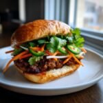Close-up of a delicious Pork Banh Mi Burger featuring a savory patty, pickled carrots, cilantro, and jalape&ntilde;os.