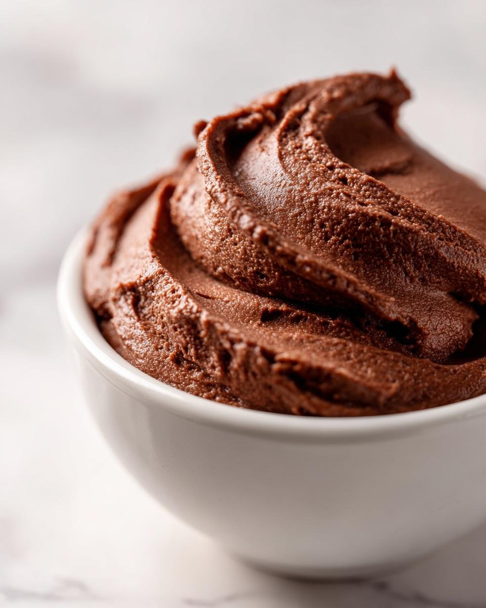 Close-up of rich, dark Dairy Free Chocolate Pudding swirled high in a small white bowl.