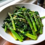 Close-up of bright green asparagus and wilted spinach in a Savory Asparagus Spinach Saute, glistening with sauce.