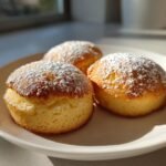 Three golden Sherlock Holmes Foggy London Tea Cakes dusted with powdered sugar on a white plate.