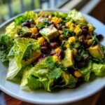 A close-up of a fresh Santa Fe Salad featuring crisp lettuce, diced avocado, black beans, and corn.