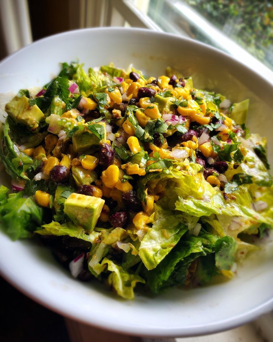 Close-up of a vibrant Santa Fe Salad featuring romaine lettuce, black beans, corn, avocado, and red onion.