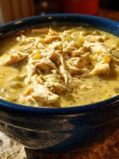 A close-up of a bowl of creamy White Chicken Chili Paleo topped with shredded chicken.